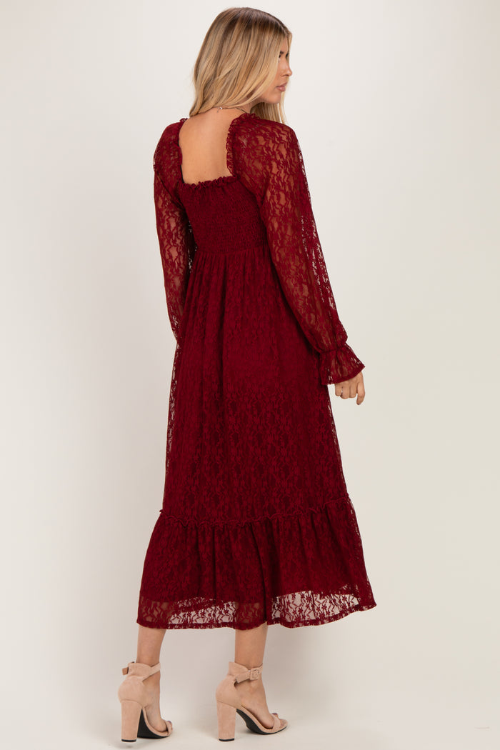 woman wearing a burgundy lace long sleeve midi dress with a ruffled hem and back details