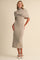 woman wearing a beige knit midi dress with a high neck and a wrap shawl over the shoulders