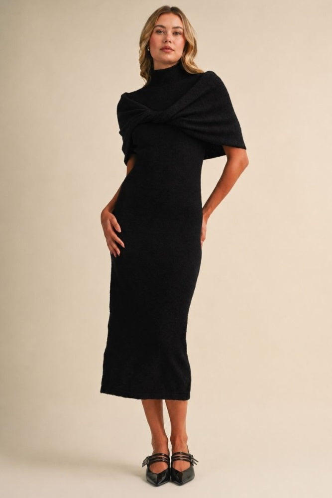 woman wearing a black fitted midi dress with a turtleneck and draped shawl-style sleeves