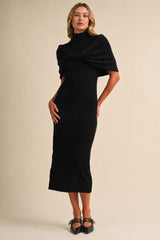 woman wearing a black fitted midi dress with a turtleneck and draped shawl-style sleeves