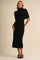 woman wearing a black fitted midi dress with a turtleneck and draped shawl-style sleeves