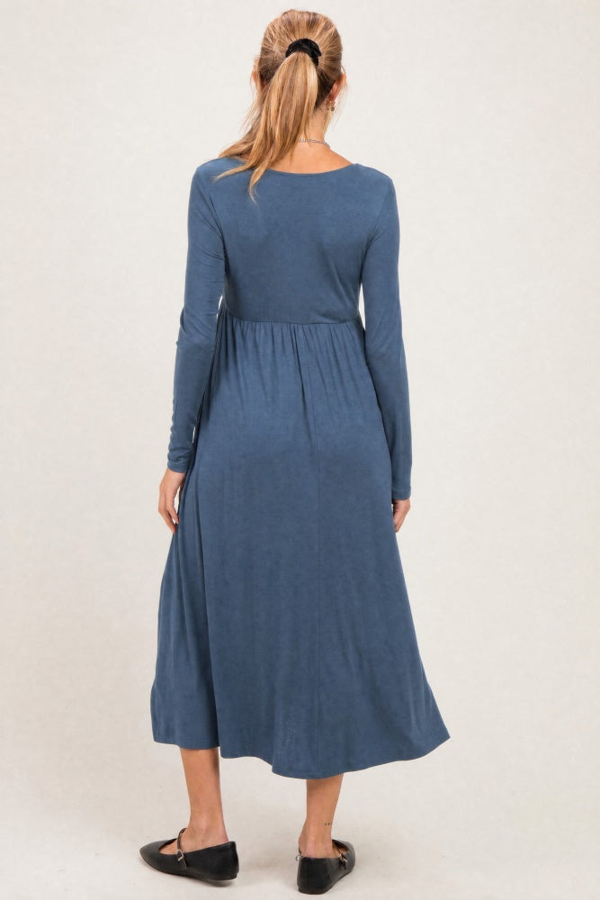 woman wearing a long sleeve blue maternity dress with a flowing skirt, showcasing a relaxed fit and gathered waist detail