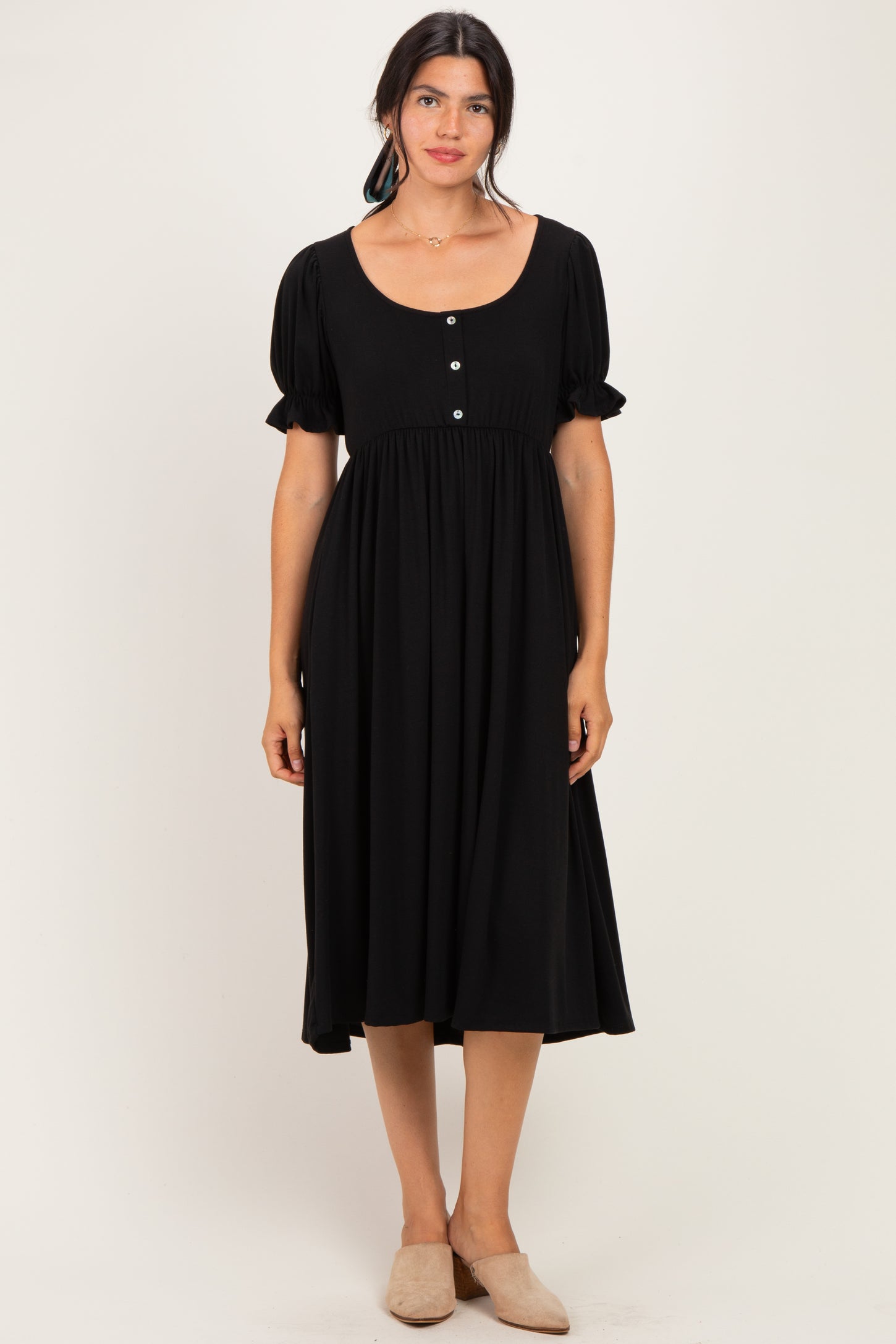 woman wearing a black midi dress with puff sleeves and button details in the front