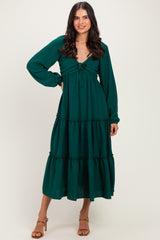 woman wearing a forest green long sleeve maxi dress with a tie front and tiered skirt