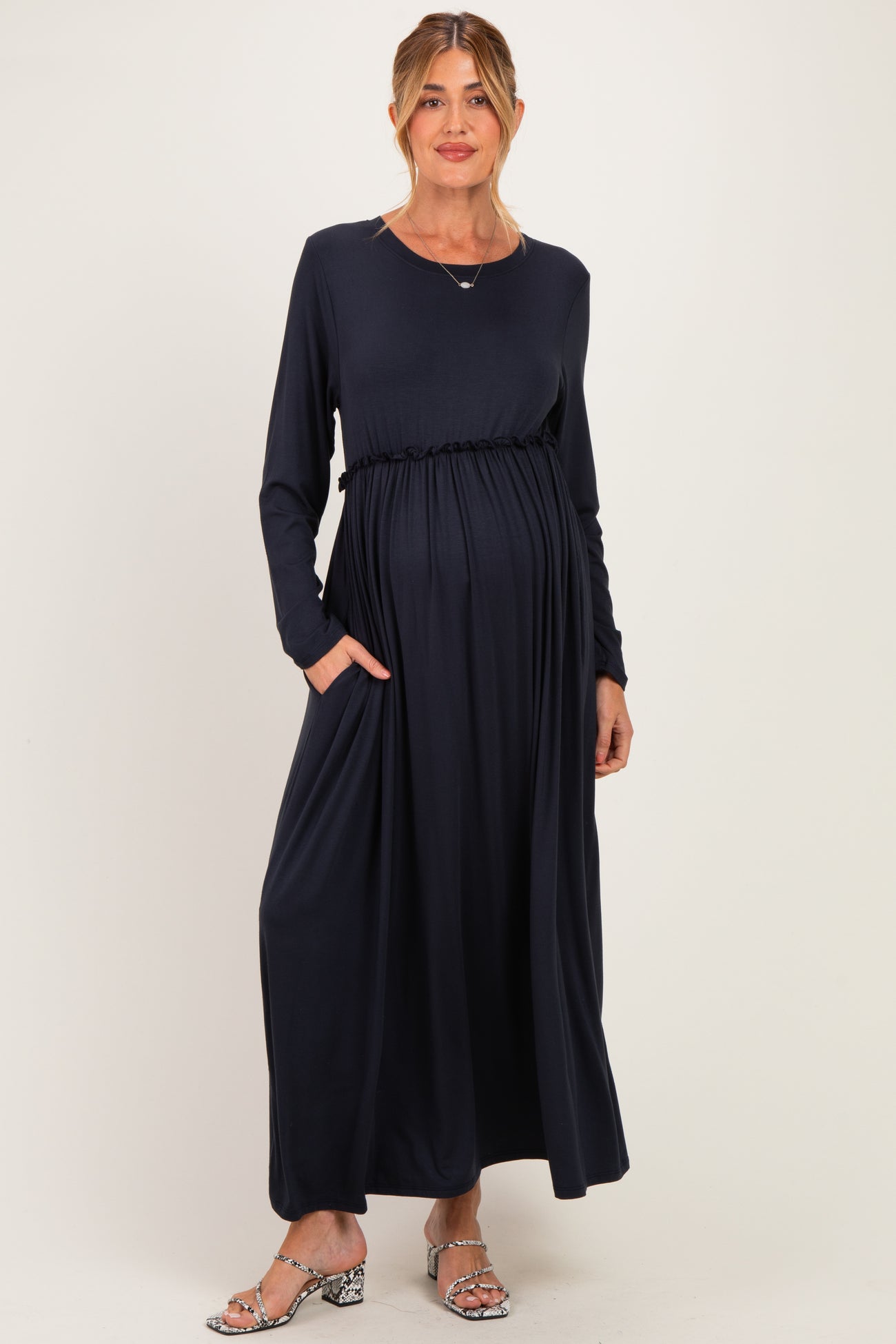 woman wearing a navy long sleeve maternity dress with a waist tie and pockets, and showing her baby bump