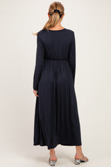 woman wearing a navy blue long sleeve maternity dress with an elastic waistband, showing a flowing silhouette from the back