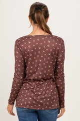 woman wearing a brown long sleeve maternity top with a floral pattern, viewed from the back