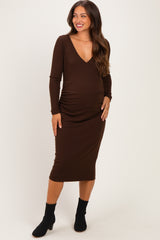 woman wearing a brown long sleeve maternity dress with a v-neckline and ruching at the baby bump