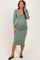 woman wearing a green long sleeve maternity dress with a v-neckline and fitted silhouette, showing her baby bump