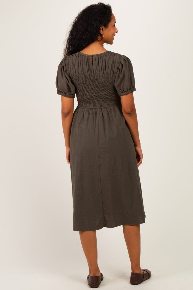 woman wearing a dark green maternity dress with a smocked bodice and short puff sleeves, seen from the back