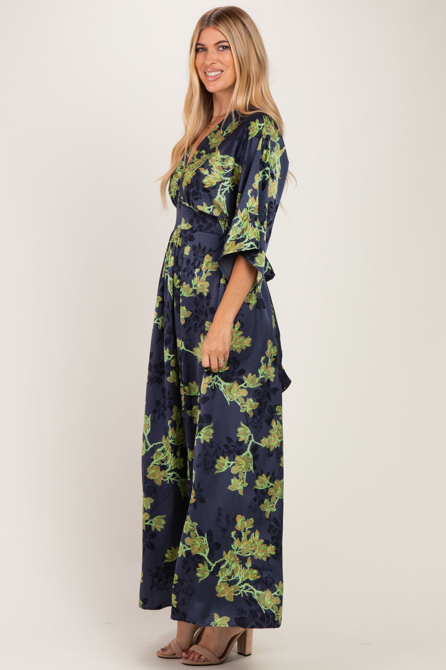woman wearing a navy blue floral maxi dress with bell sleeves and a tie waist detail