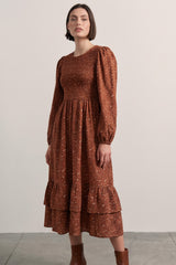 woman wearing a brown floral long sleeve midi dress with puff sleeves and tiered ruffle hem