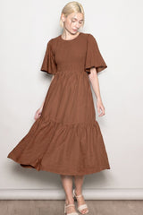woman wearing a brown smocked bodice midi dress with flutter sleeves and a tiered skirt