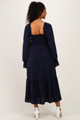 woman wearing a navy blue maternity dress with a smocked back and ruffled tiered hem