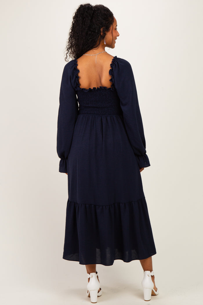 woman wearing a navy blue maternity dress with a smocked back and ruffled tiered hem