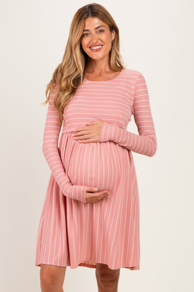 woman wearing a pink striped long sleeve maternity dress and holding her baby bump