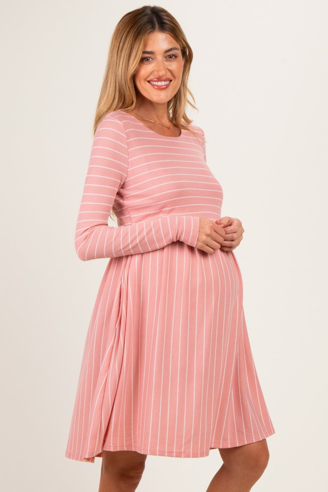 woman wearing a pink striped long sleeve maternity dress with a visible baby bump