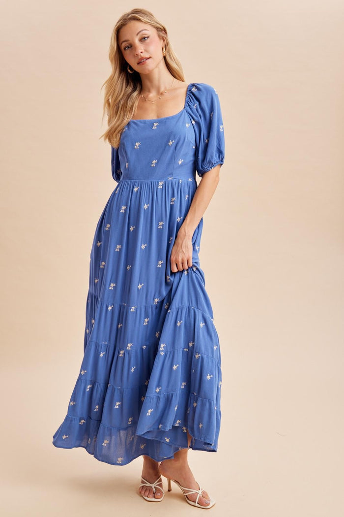 woman wearing a blue maxi dress with puff sleeves and floral embroidery