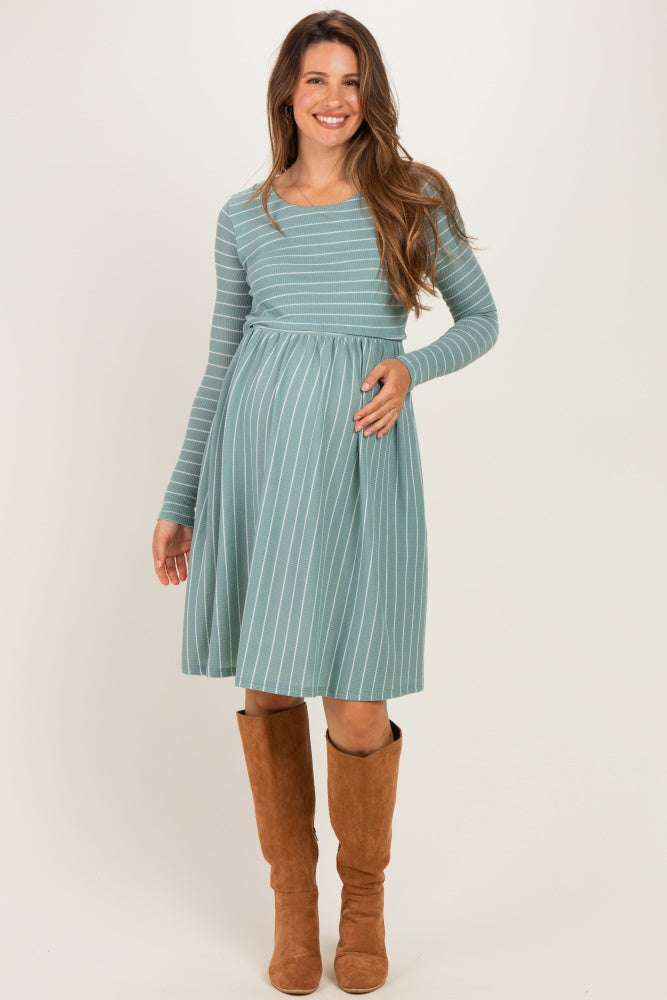 woman wearing a light blue striped long sleeve maternity dress and holding her baby bump