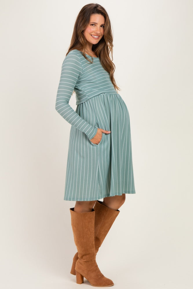 woman wearing a teal striped maternity dress with pockets and a visible baby bump, paired with brown knee-high boots