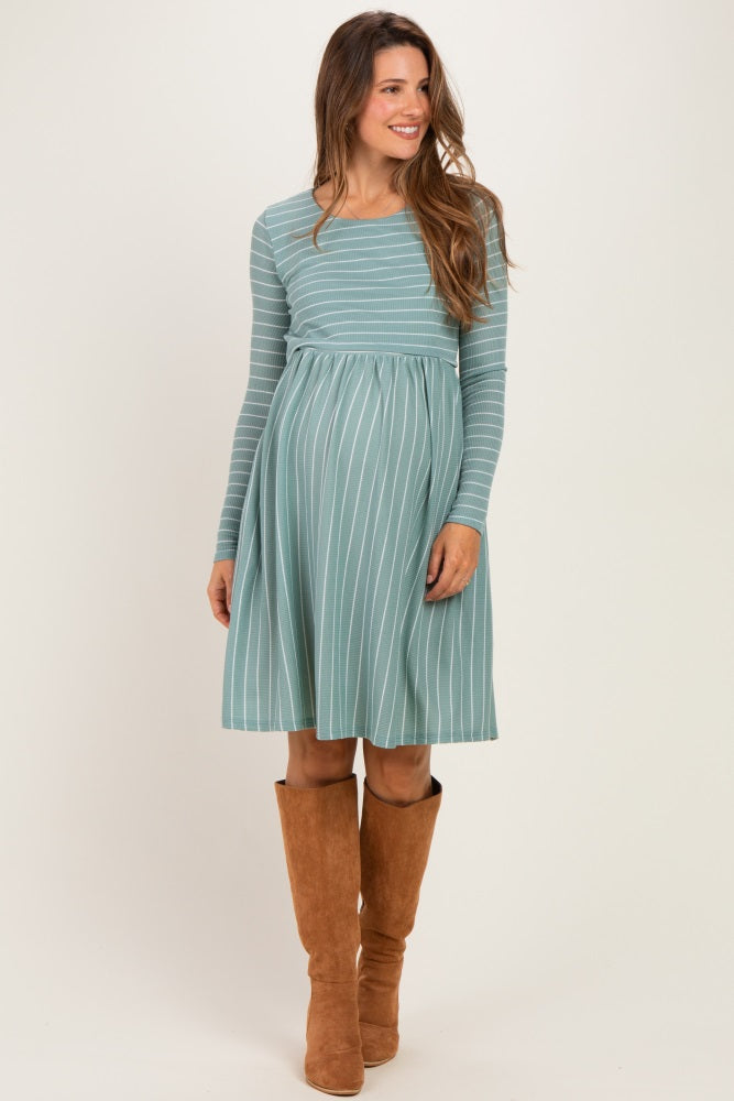 woman wearing a teal striped maternity dress with long sleeves and a fitted waist, showing her baby bump