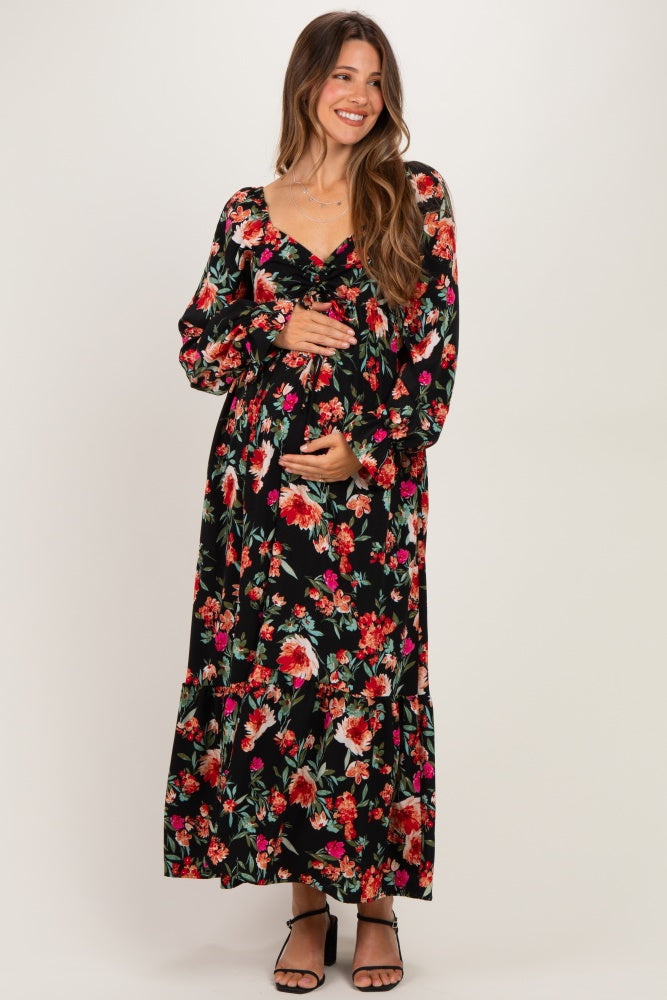woman wearing a black floral maternity maxi dress with long sleeves and a baby bump visible
