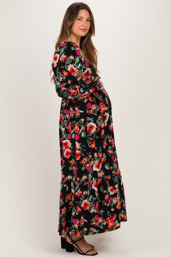 woman wearing a black floral maternity maxi dress with long sleeves and a flowy hem, showcasing her baby bump