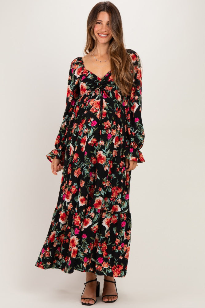 woman wearing a black floral maternity maxi dress with long sleeves and a baby bump visible