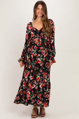 woman wearing a black floral maternity maxi dress with long sleeves and a baby bump visible