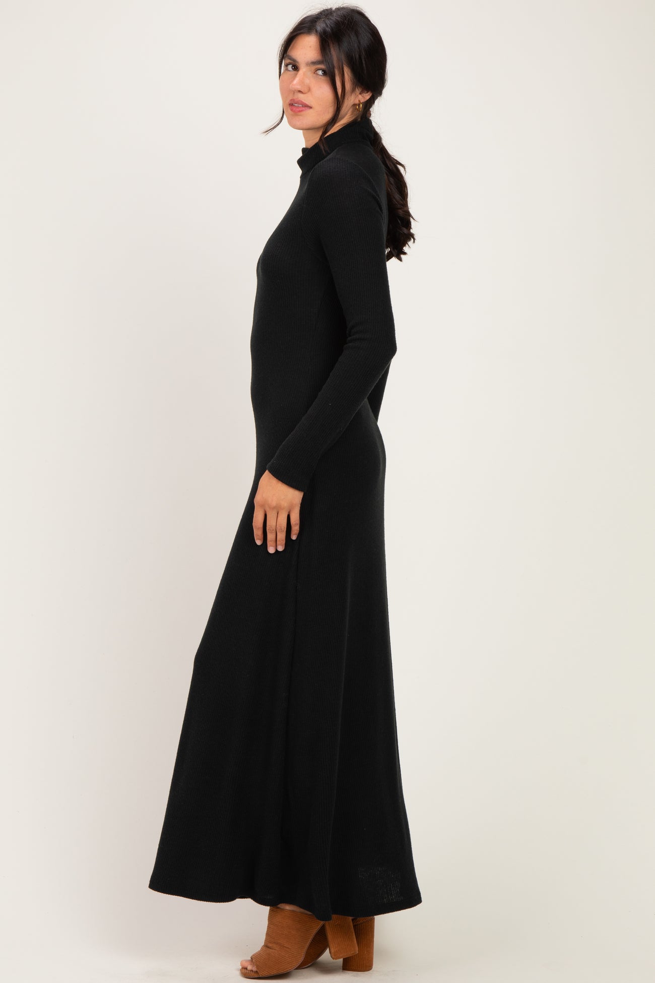 woman wearing a black long sleeve maxi dress with a mock neckline and side slit