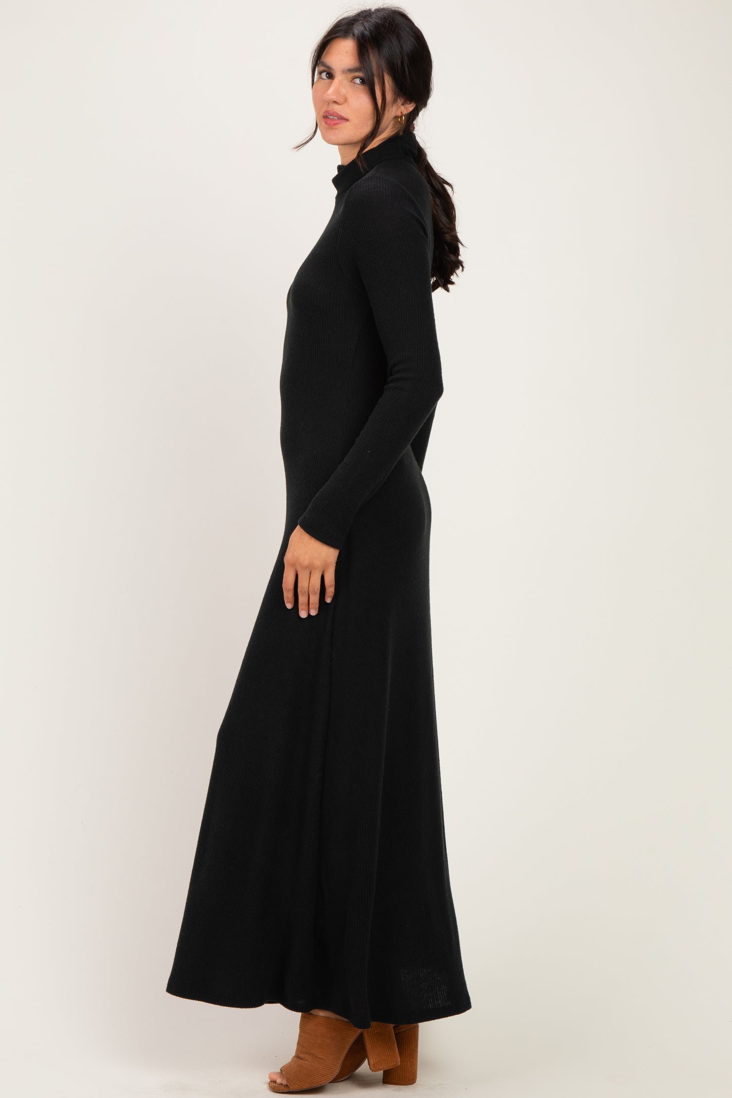 woman wearing a black long sleeve maxi dress with a mock neckline and side slit