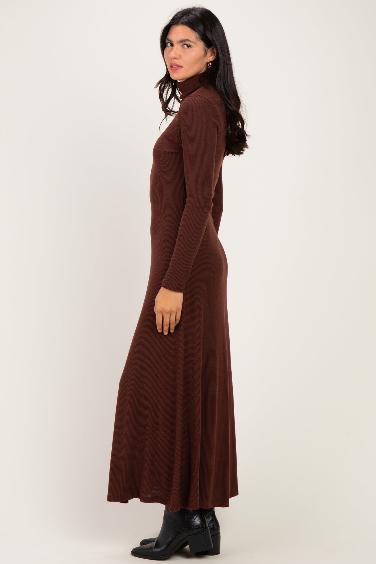 woman wearing a fitted brown ribbed turtleneck maxi dress with long sleeves and a flared skirt