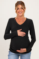 woman wearing a black long sleeve maternity top and holding her baby bump