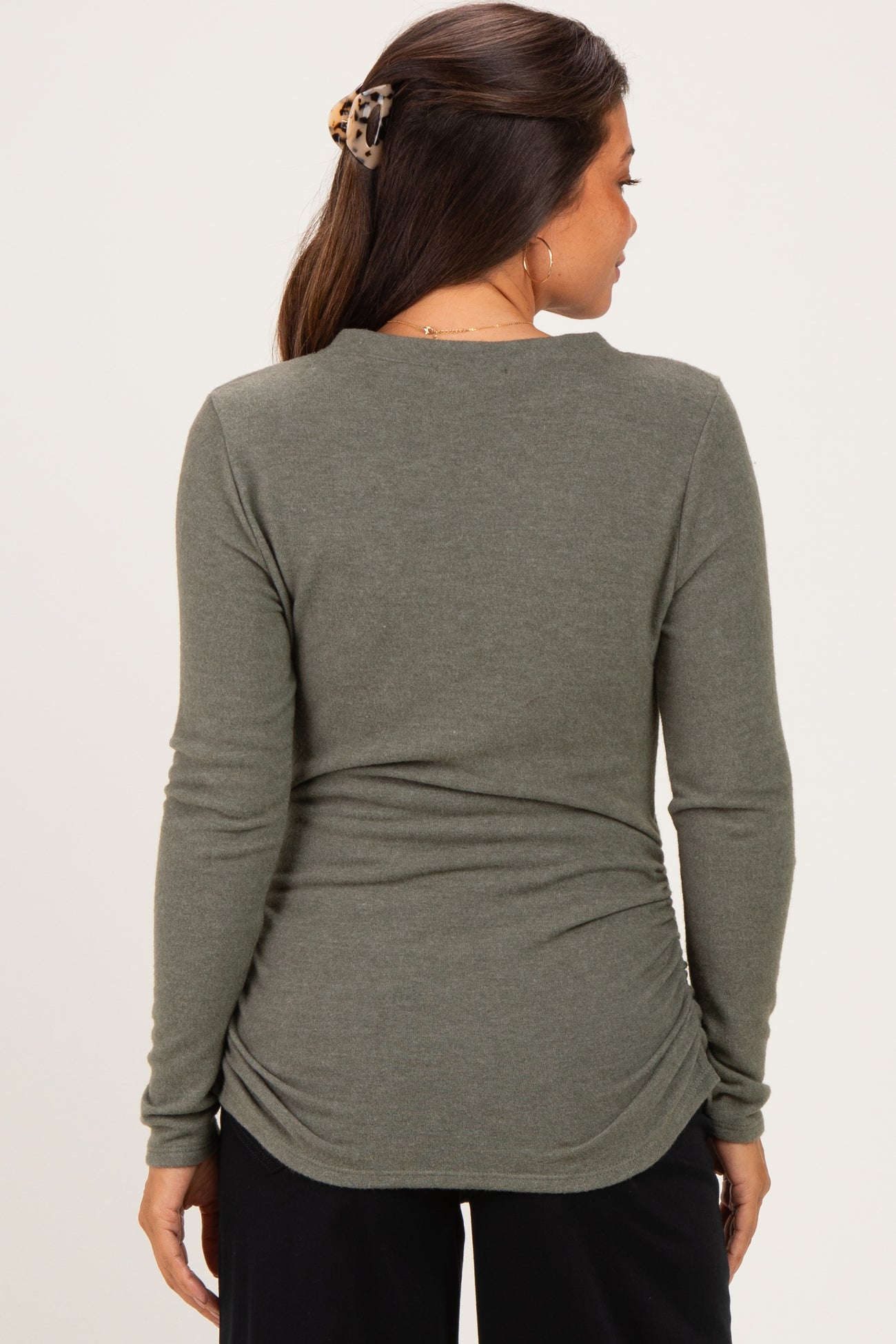 woman wearing a dark green maternity long sleeve top with gathering at the back