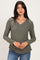 woman wearing an olive green long sleeve v-neck top with a relaxed fit and light knit texture