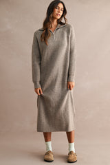 woman wearing a light gray ribbed knit long sleeve sweatshirt dress with a quarter zip and side slits