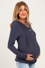 woman wearing a navy blue maternity hoodie with buttons and a baby bump visible