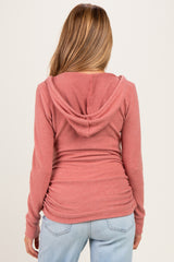woman wearing a dusty rose maternity hoodie with a back view, featuring a hood and ruched sides