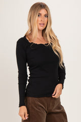 woman wearing a black long sleeve fitted top with a ruffled neckline and styled hair