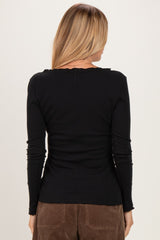 woman wearing a black long sleeve ribbed top with a scalloped neckline and fitted silhouette