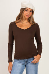 woman wearing a brown ribbed maternity top with a scalloped neckline and long sleeves