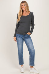woman wearing a gray long sleeve top with scalloped edges and blue straight-leg jeans, standing in white sneakers