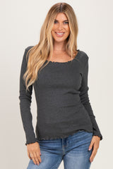 woman wearing a charcoal gray long sleeve top with a scalloped neckline and hem, paired with blue jeans