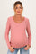 woman wearing a pink long sleeve maternity top with ruffle trim and a visible baby bump