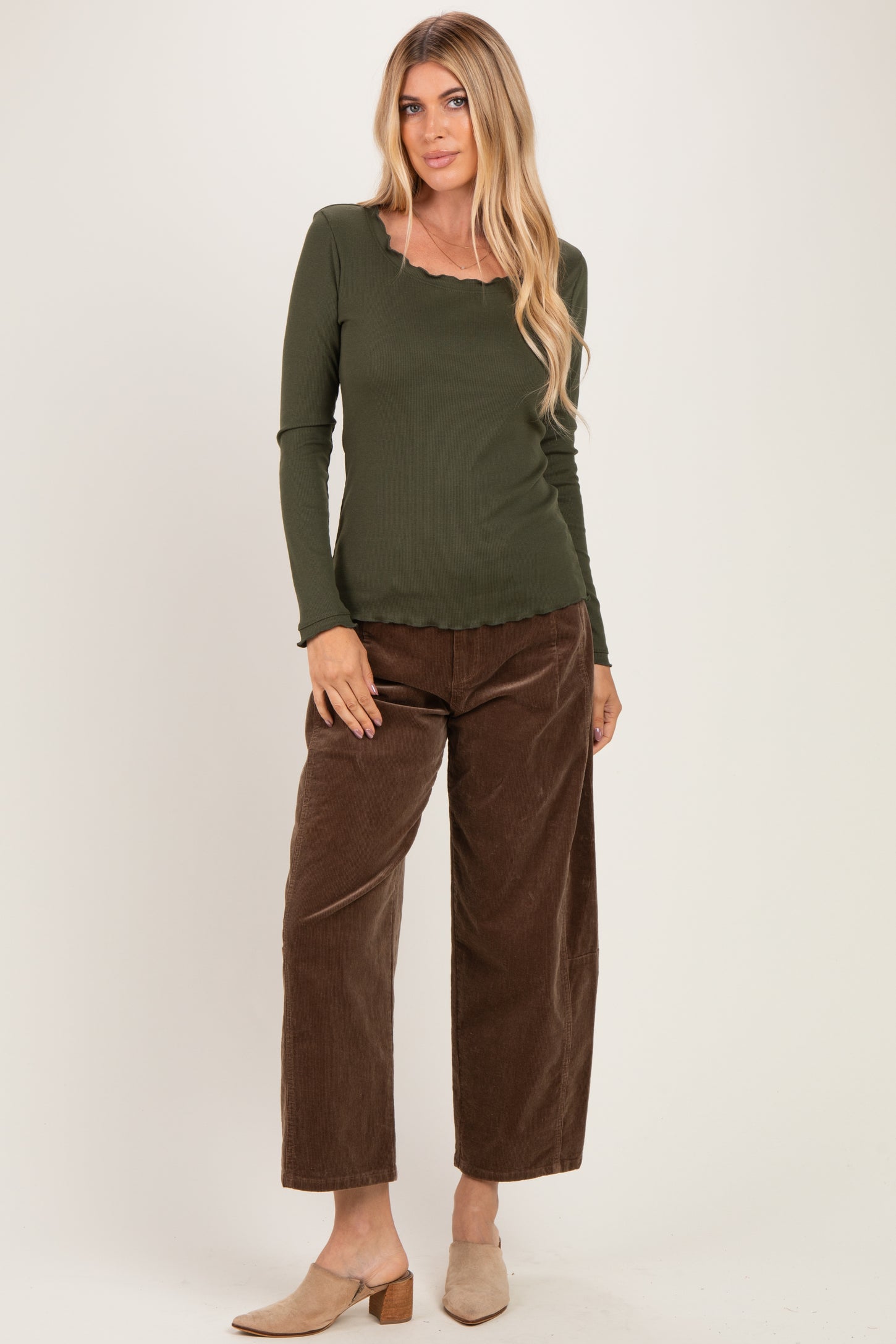 woman wearing an olive green long sleeve top with a scalloped neckline and brown wide-leg corduroy pants