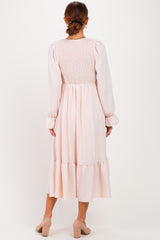 woman wearing a blush pink midi dress with smocked back and ruffled hem, viewed from the back