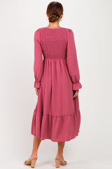 woman wearing a long pink smocked back dress with long sleeves and tiered hemline