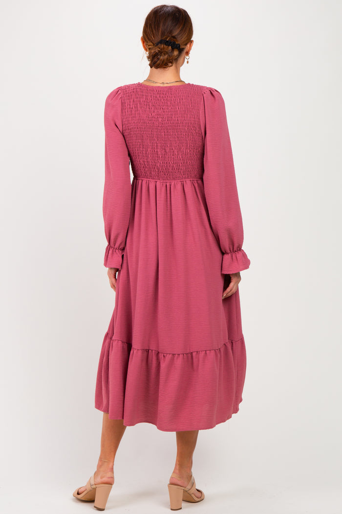 woman wearing a long pink smocked back dress with long sleeves and tiered hemline