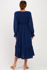 woman wearing a navy blue long sleeve smocked back dress with a tiered hem and puff sleeves
