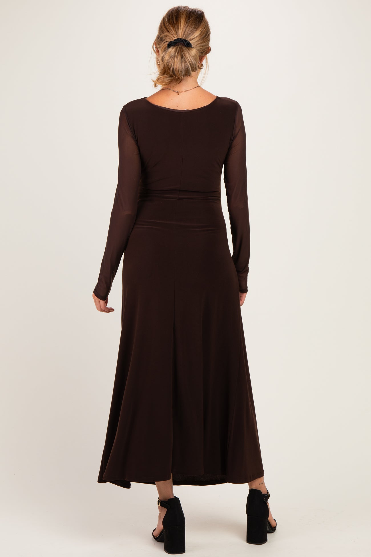 woman wearing a brown long sleeve maternity dress with a flowing skirt and a fitted bodice, shown from the back